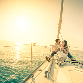 Young couple in love on sailboat with champagne at sunset