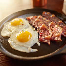fried bacon and eggs in iron skillet