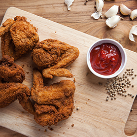 fried chicken wings with tomato sauce on wooden board