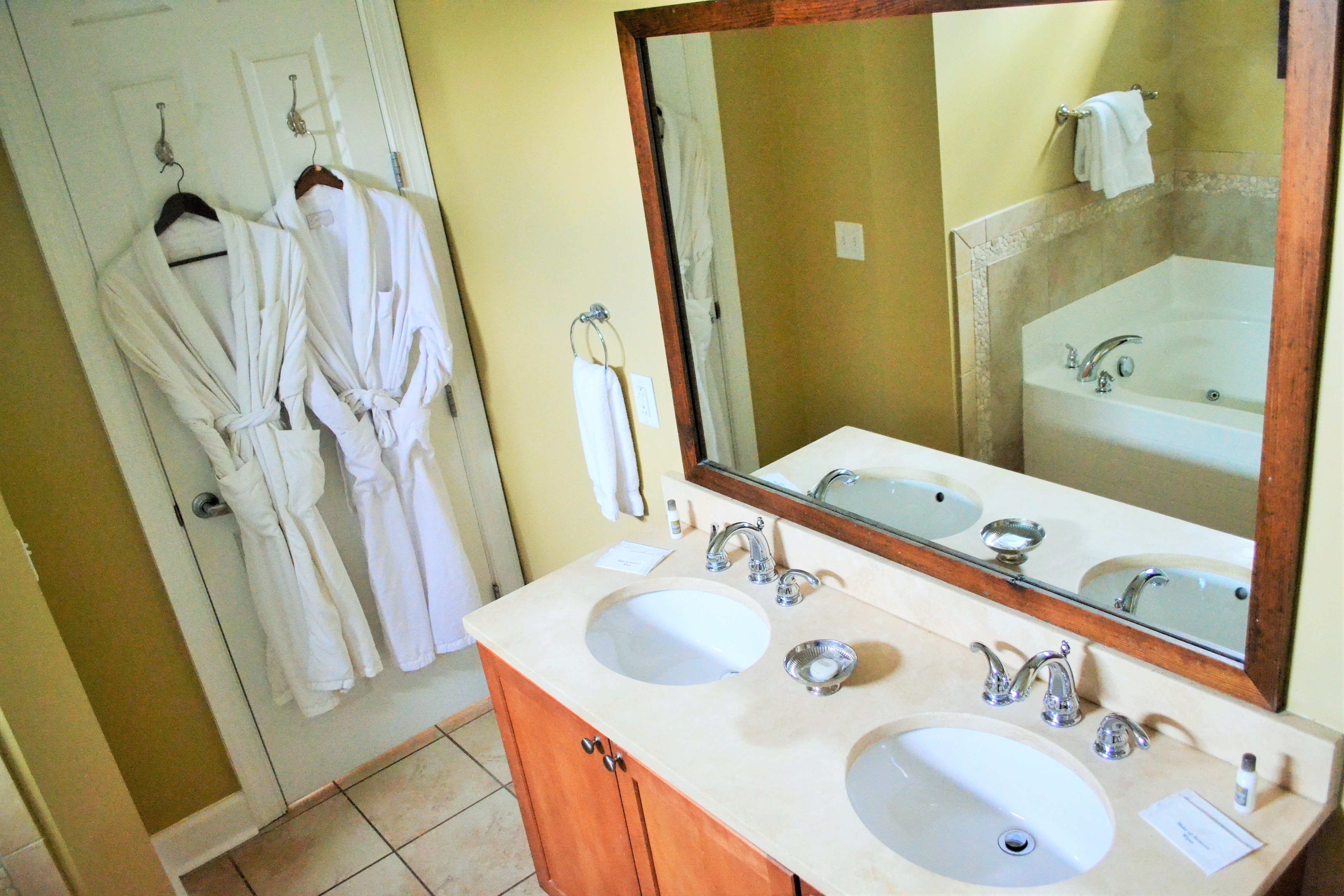 bathroom sinks, a mirror, and 2 hanging bathrobes