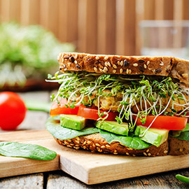 sprouts avocado tomato spinach chickpeas burger rye sandwich